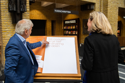 911033 Afbeelding van wethouder Anke Klein en directeur Ton van Vlimmeren met het gastenboek van de Bibliotheek Neude ...